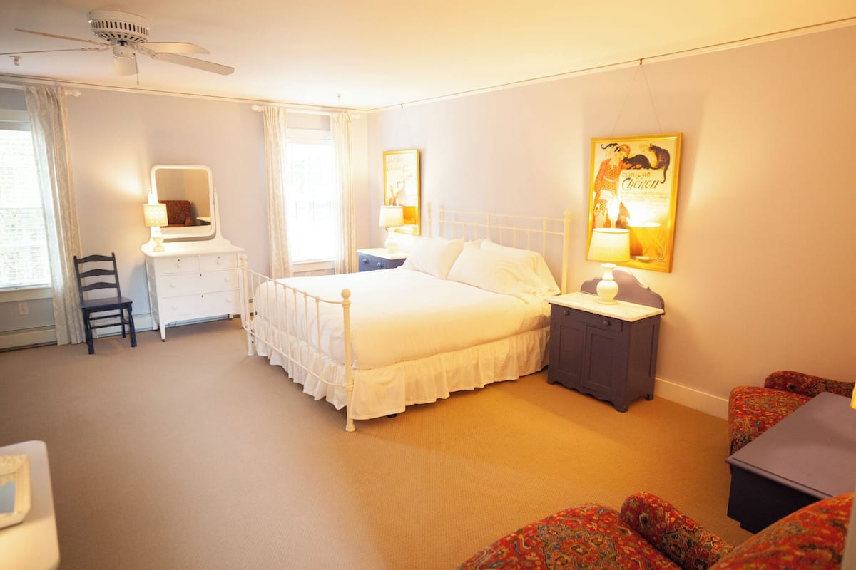 A bedroom with a bed, bedside tables, a desk, and a chair.