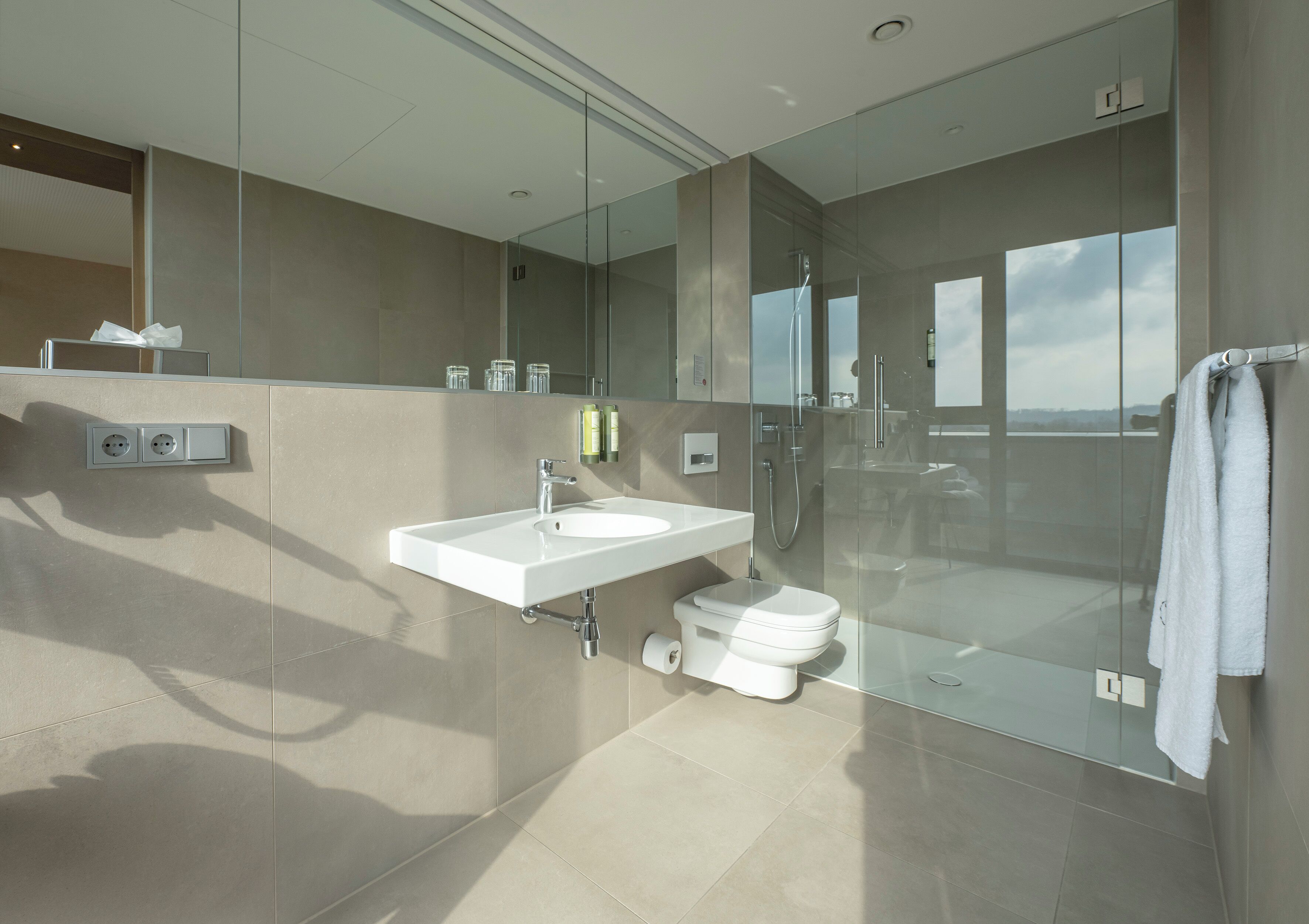 Un baño moderno con ducha de vidrio, lavamanos y retrete.