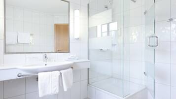 A modern bathroom with a glass-enclosed shower, a white sink, and a large mirror.