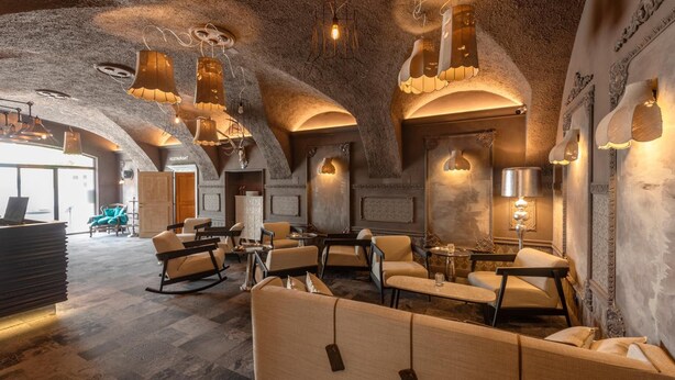 A modern interior with a stone ceiling, ambient lighting, and a mix of seating arrangements including sofas and chairs.