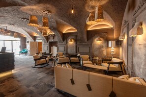 A modern interior with a stone ceiling, ambient lighting, and a mix of seating arrangements including sofas and chairs. - Hotel Gasthof Fischer (Marchtrenk)