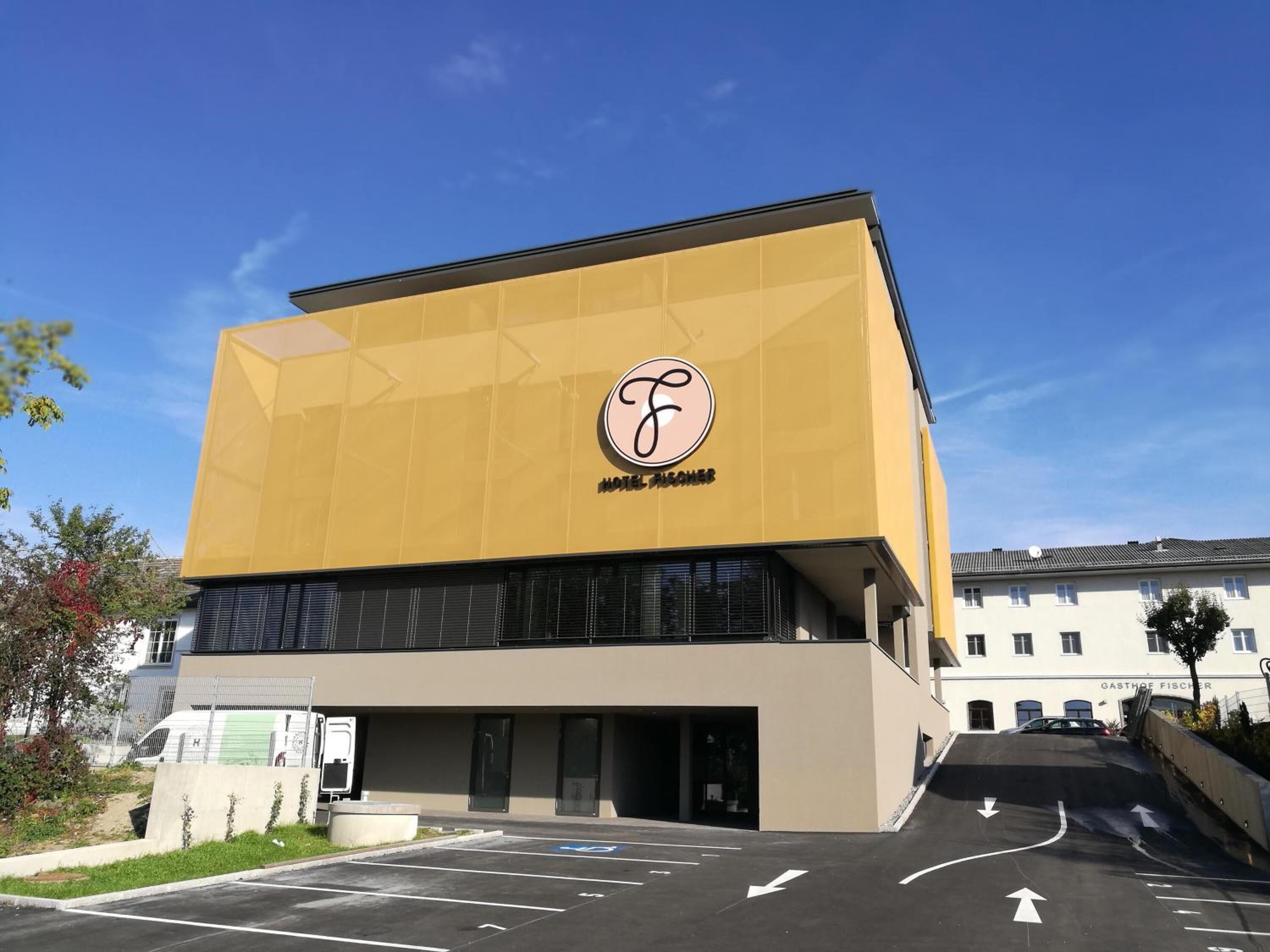 A modern hotel building with a prominent logo on the facade.