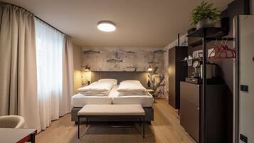 Una habitación de hotel con cama, mesitas de noche, un banco, un escritorio, un refrigerador y una pared con motivos de peces.
