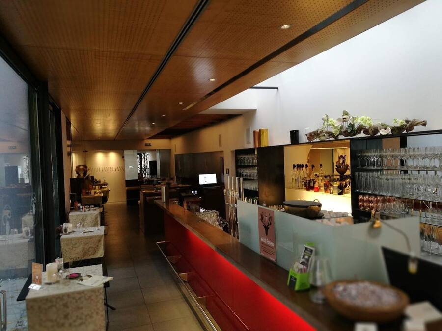 A bar area with a long counter, seating, and a display of glasses and bottles.