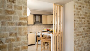 Una cocina con paredes de piedra, armarios de madera, una estufa y un comedor separado por una partición de madera.