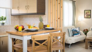 Una cocina con armarios de madera, una mesa de comedor con sillas, un frutero y una piña.
