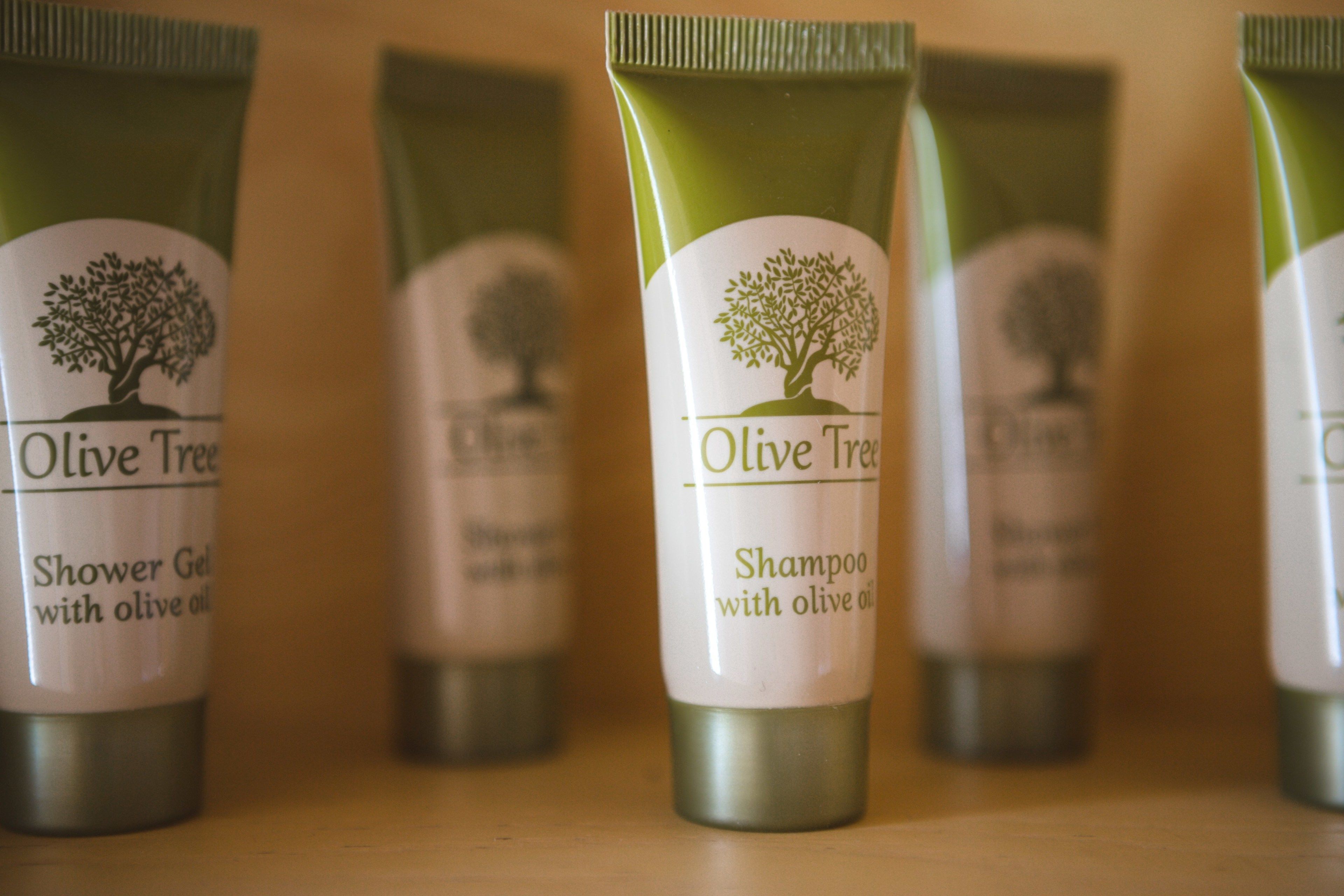 Four tubes of Olive Tree shampoo and shower gel on a shelf.