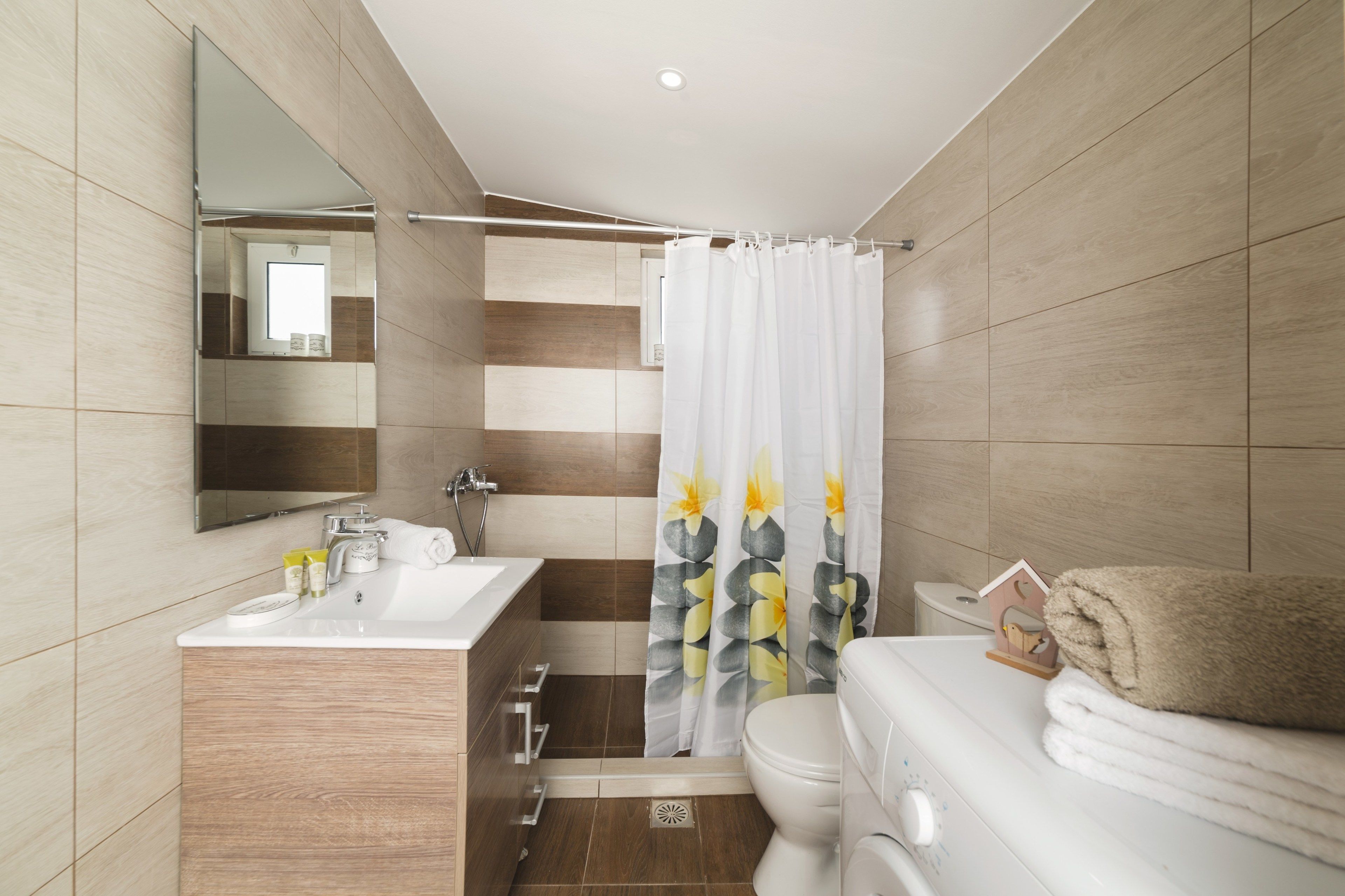 A modern bathroom with a sink, toilet, and shower curtain.
