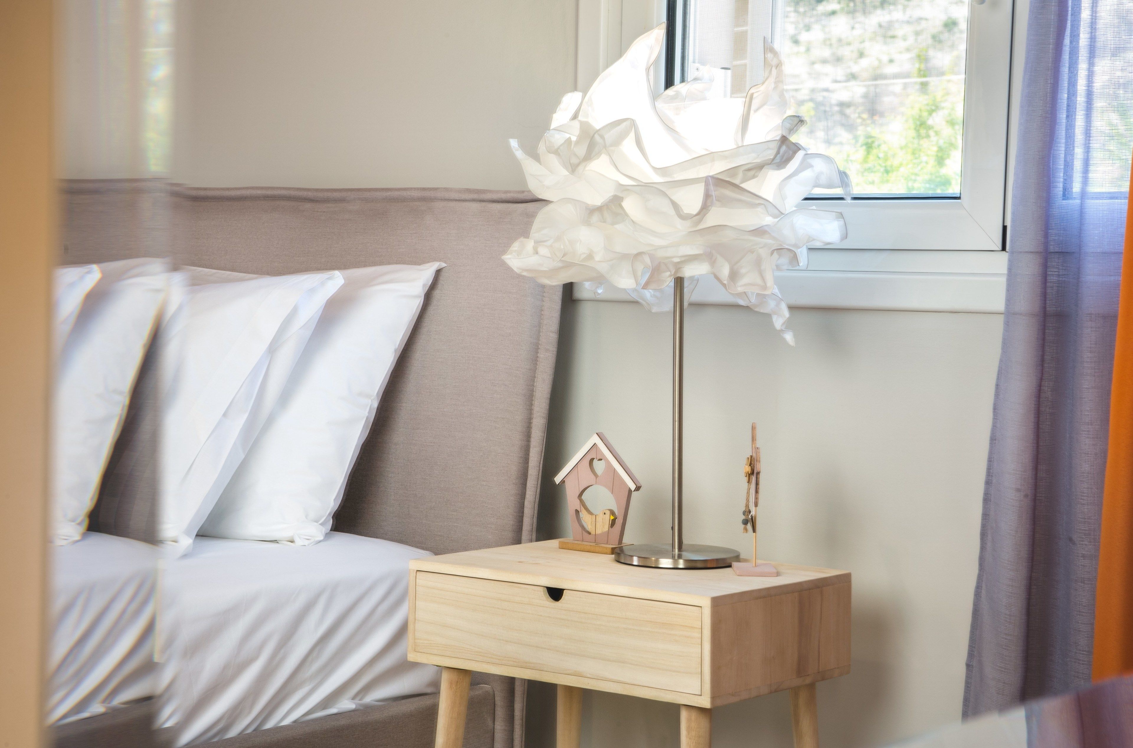 Une chambre à coucher avec un lit, une table de chevet avec une lampe et une fenêtre avec des rideaux.