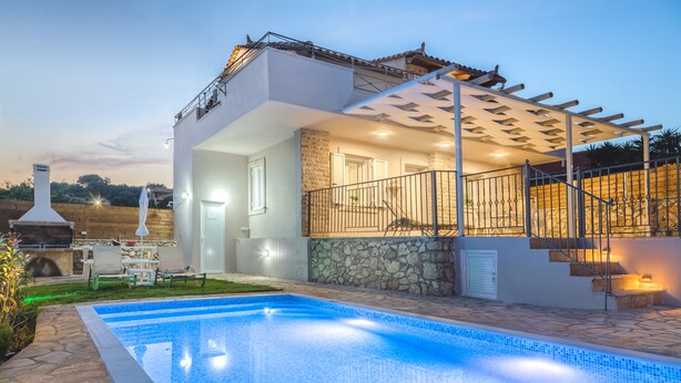 Una casa moderna con piscina, muros de piedra y un área exterior cubierta con escaleras.