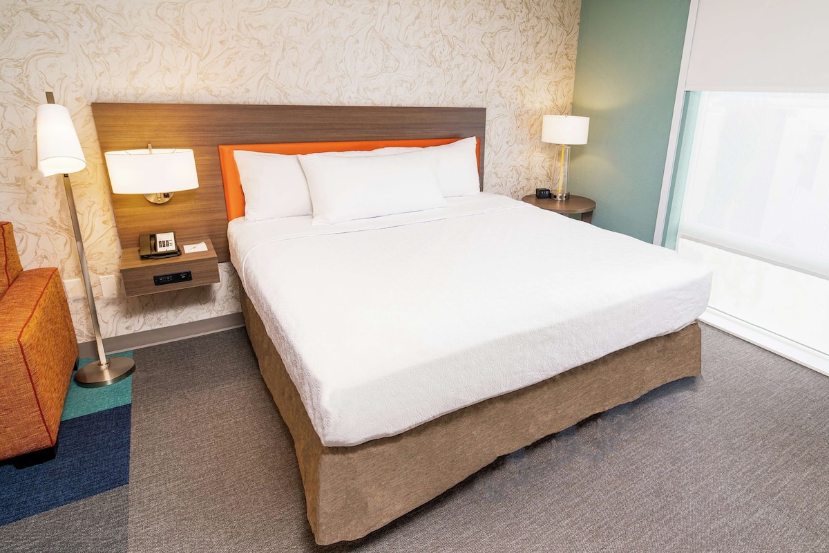 A neatly made bed with white linens, a wooden headboard, and two bedside lamps.