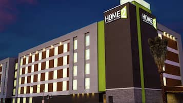 A modern hotel building with a sign reading "HOME 2 SUITES BY HILTON".