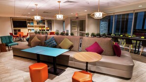 A modern lounge area with a sofa, ottomans, a table, and a bar area with chairs. - Home2 Suites by Hilton Las Vegas Stadium District (Las Vegas)
