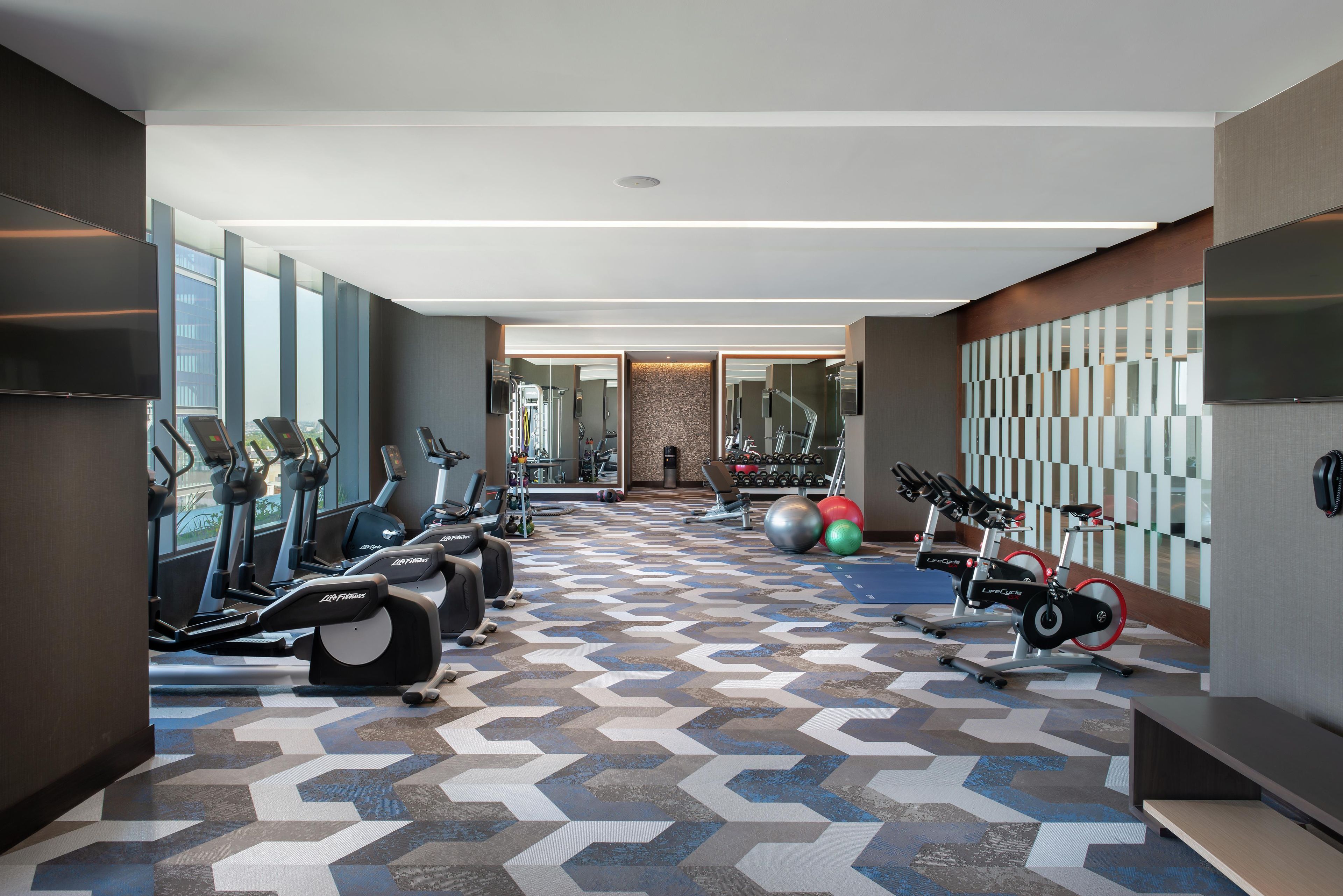Un gimnasio moderno con cintas de correr, elípticas y pelotas de ejercicio.