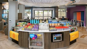A self-service beverage station with a variety of drinks and snacks, a refrigerated display, and a coffee machine.
