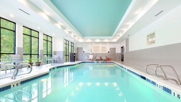 A swimming pool with clear blue water, surrounded by windows and indoor seating.