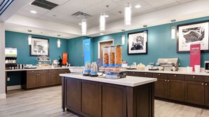 A modern cafe with a central island, coffee machines, and a variety of food items.