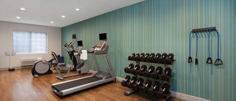 A gym with treadmills, elliptical machines, and a rack of dumbbells.