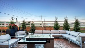 An outdoor patio area with a sectional sofa, a dining table, and a water feature.