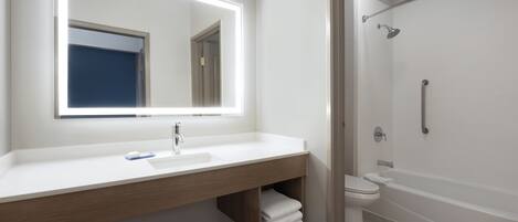 A modern bathroom with a large mirror, a sink, a toilet, and a shower.