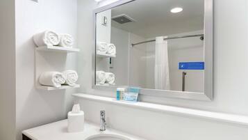 A modern bathroom with a large mirror, white sink, and towel racks.