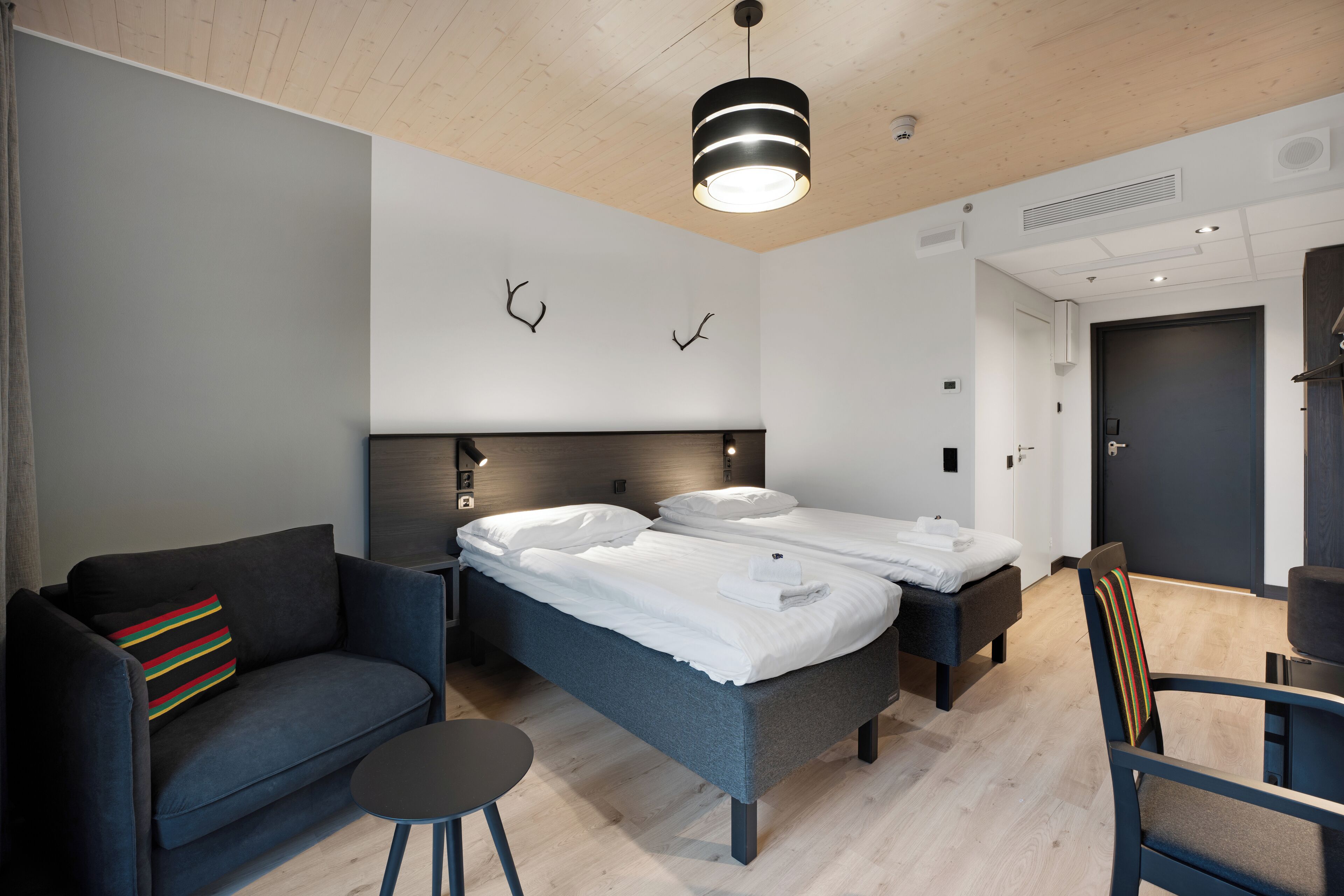 Una habitación de hotel moderna con una cama, un sofá, una mesita y una silla.