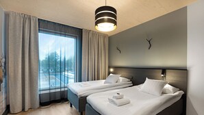 Una habitación de hotel moderna con dos camas, un ventanal con cortinas, techo de madera y una lámpara de pared.