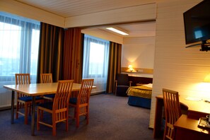 Cozy retreat with a single bed, dining table, and desk, perfect for a relaxing stay.