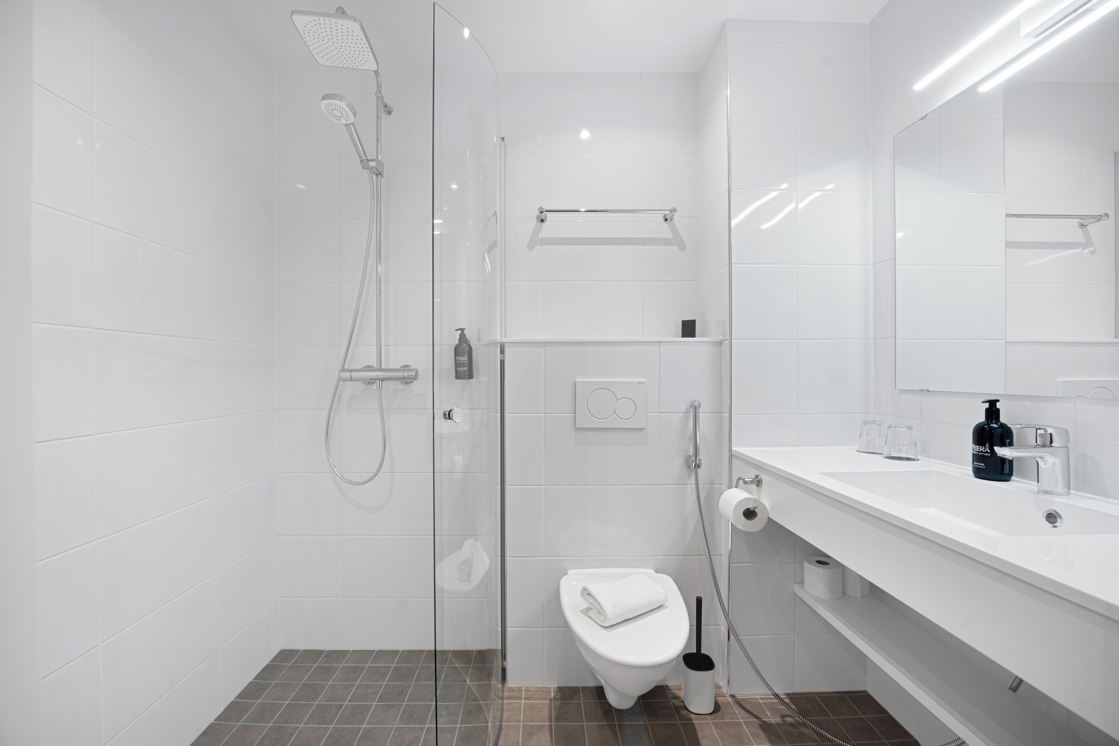 Un baño moderno con ducha envuelta en vidrio, inodoro y lavabo con espejo.