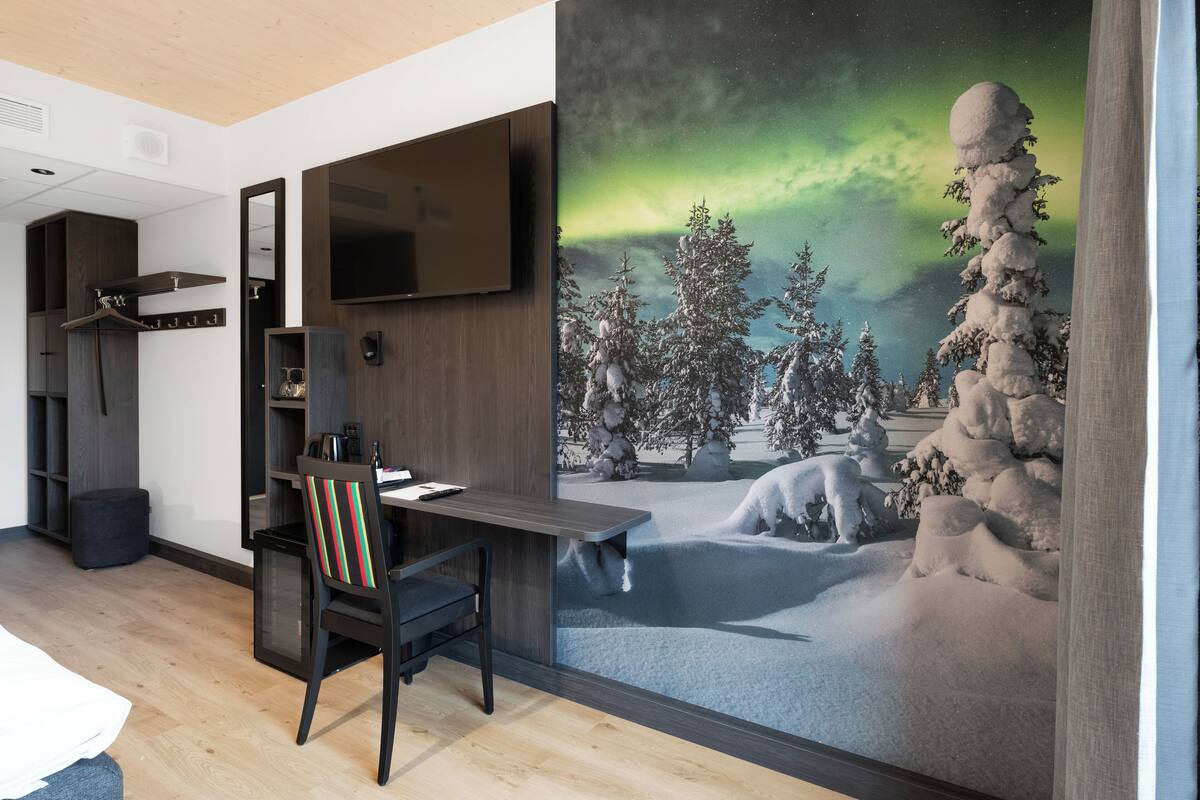 A room with a desk, chair, and a large wall mural of a snowy landscape with trees and a night sky.