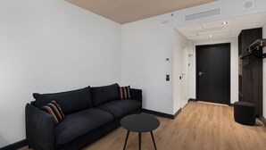 Una sala moderna con un sofá negro, una mesa redonda negra y piso de madera.