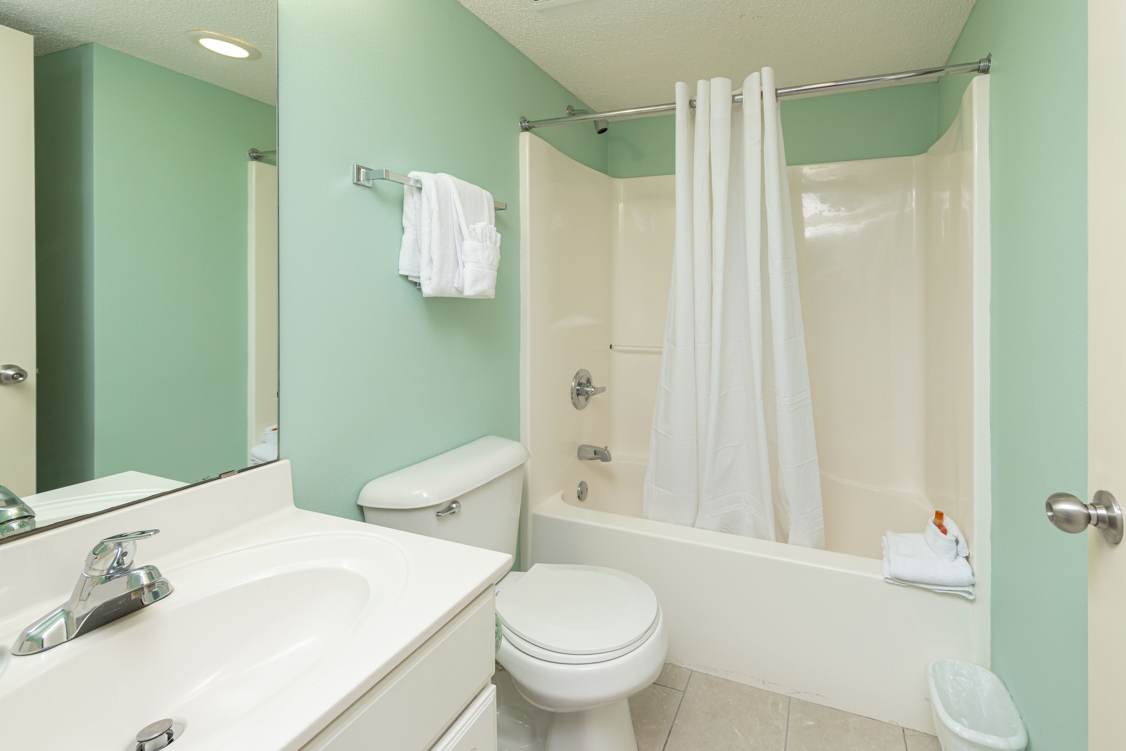A bathroom with a sink, toilet, bathtub, and a shower curtain.