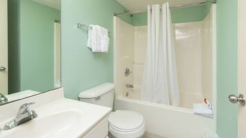 A bathroom with a sink, toilet, bathtub, and a shower curtain.