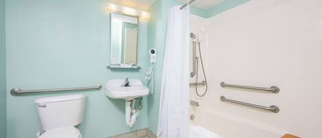 A bathroom with a toilet, sink, shower, and grab bars.