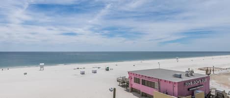 A pink building labeled "Pink Pony Pub" on a beach with a clear sky.