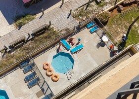 Vista aérea de una zona de piscina con una pileta rectangular, sillas de descanso y una terraza con barandilla.