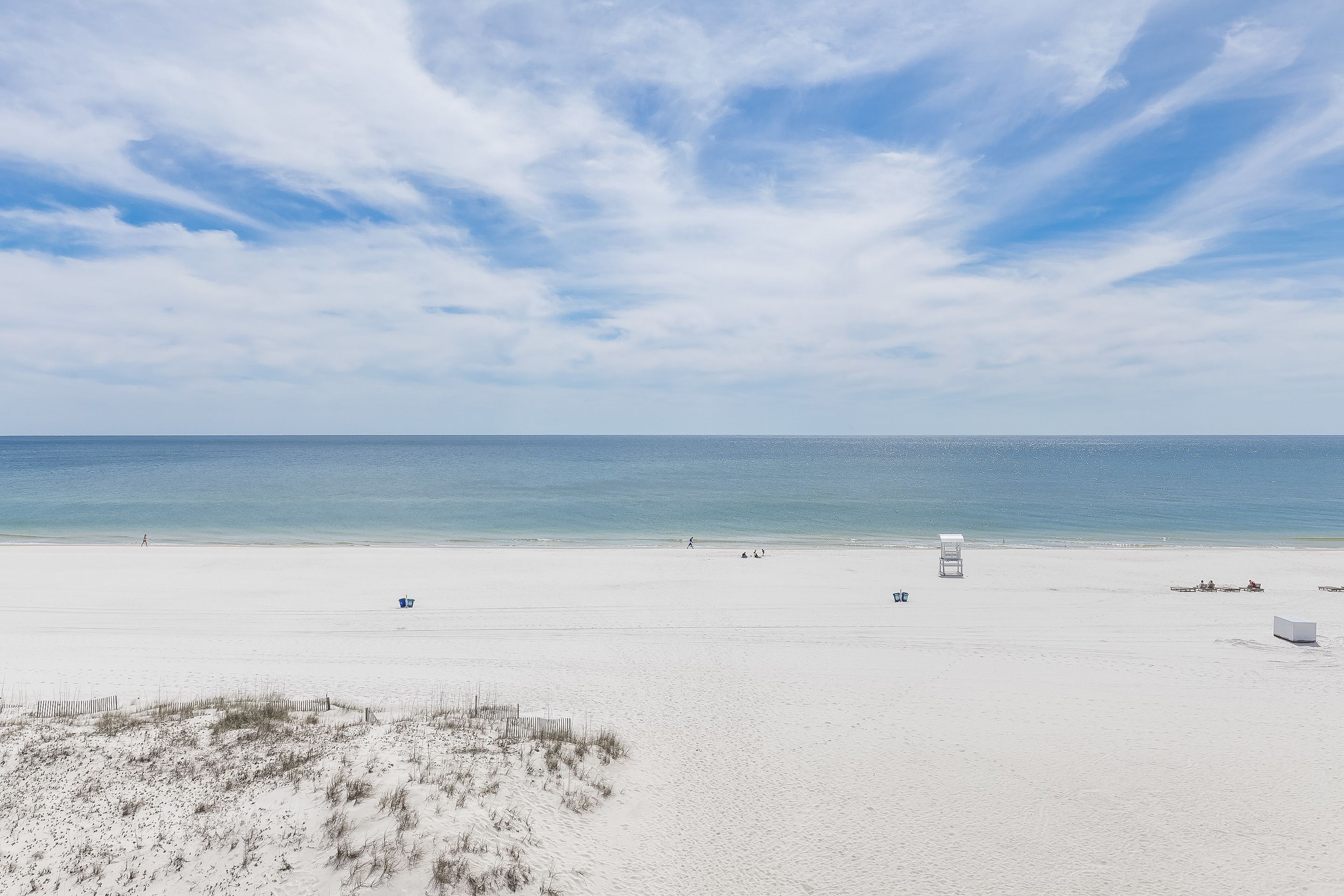 Une vaste plage de sable fin, avec un ciel dégagé et une mer calme.