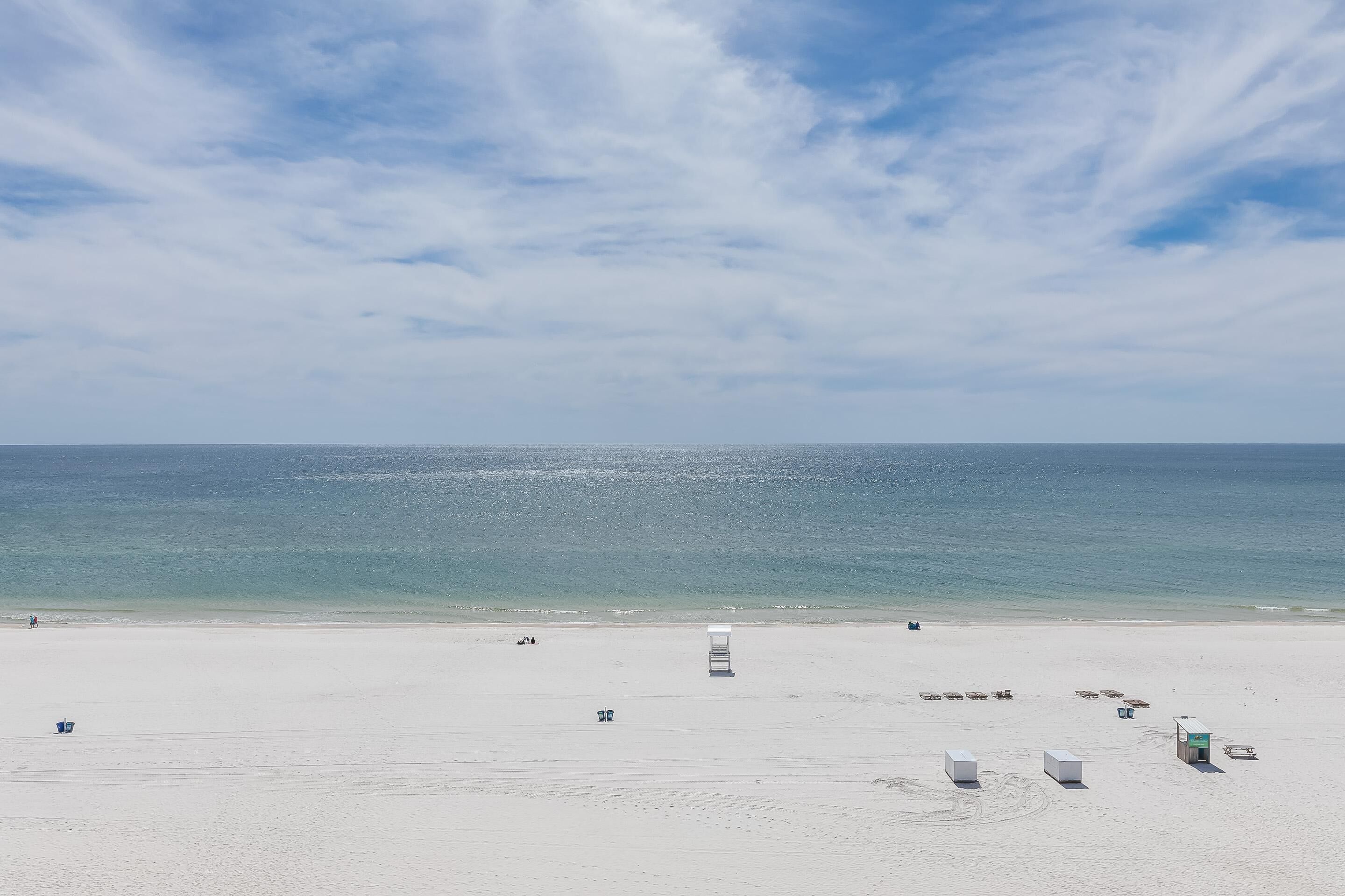 Una playa con una torre de salvavidas, sillas y sombrillas.