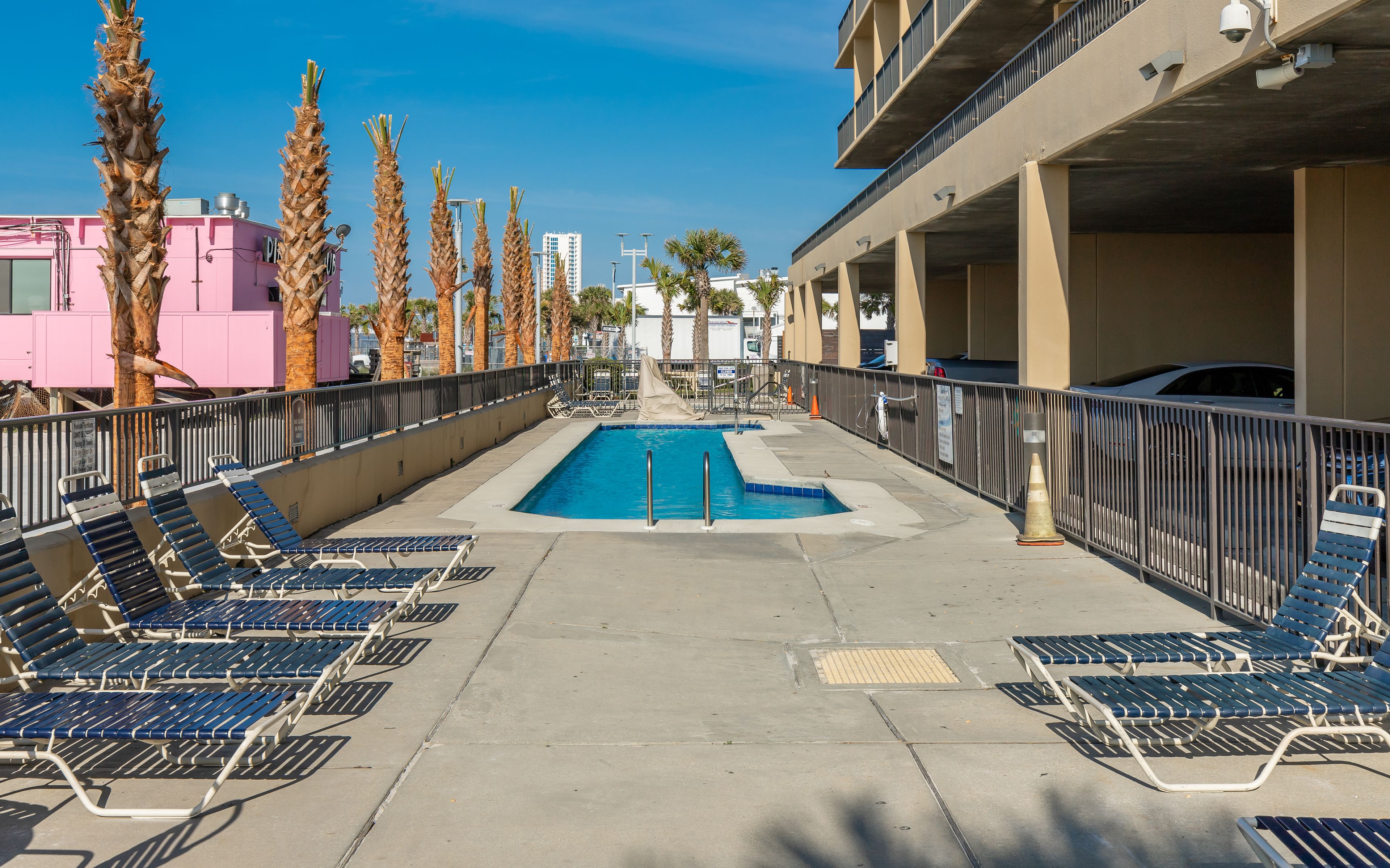 A pool area with lounge chairs and palm trees.