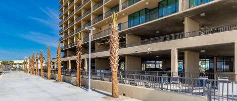A multi-story parking garage with a row of palm trees along the sidewalk.
