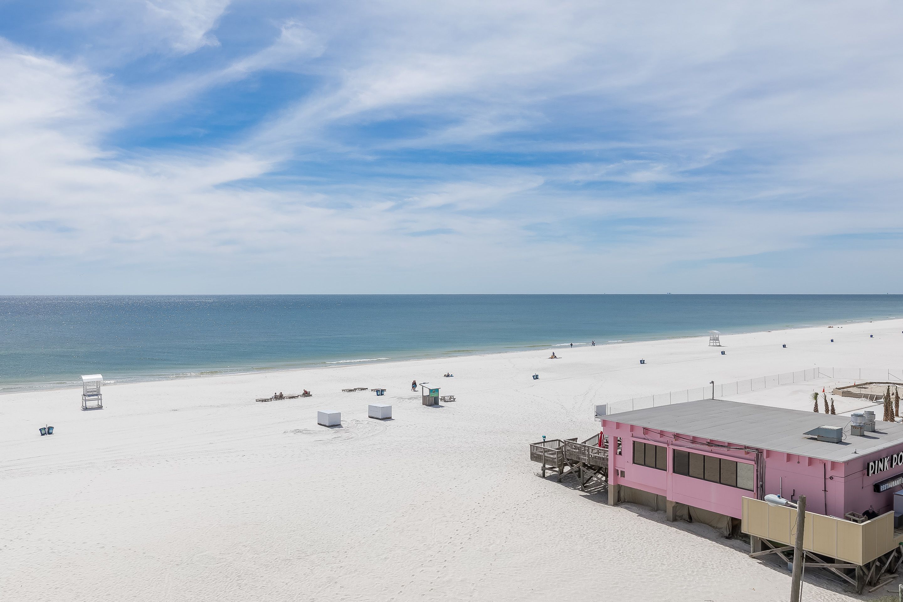 A beach with a pink lifeguard station and a clear sky.