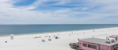 A beach with a pink lifeguard station and a clear sky.