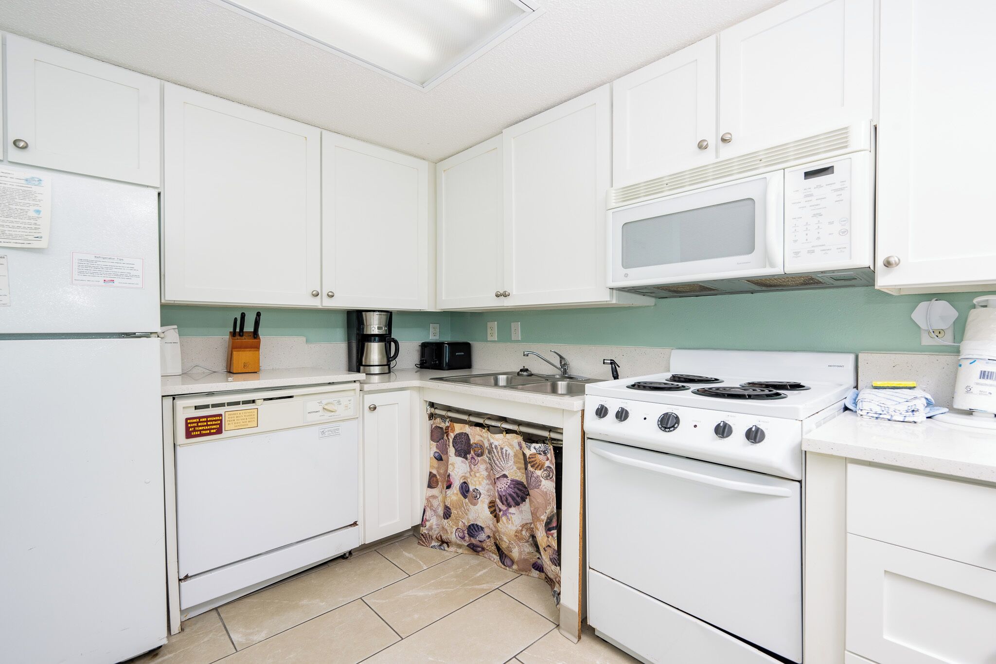 A compact kitchen with white cabinets, a microwave, a stove, and a dishwasher.