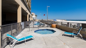A rooftop pool area with lounge chairs, a hot tub, and a view of the beach. - Phoenix All Suites (Gulf Shores)