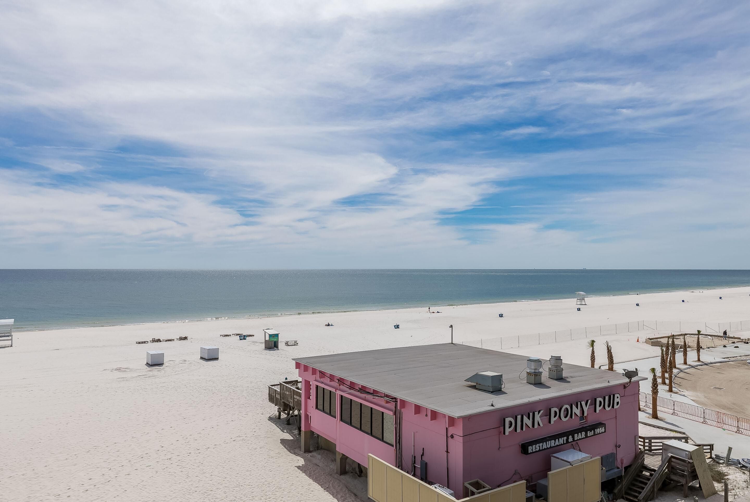 A pink building named 'Pink Pony Pub' with a beach view, located on a sandy beach.