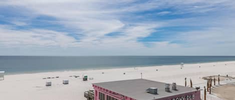 A pink building named 'Pink Pony Pub' with a beach view, located on a sandy beach.