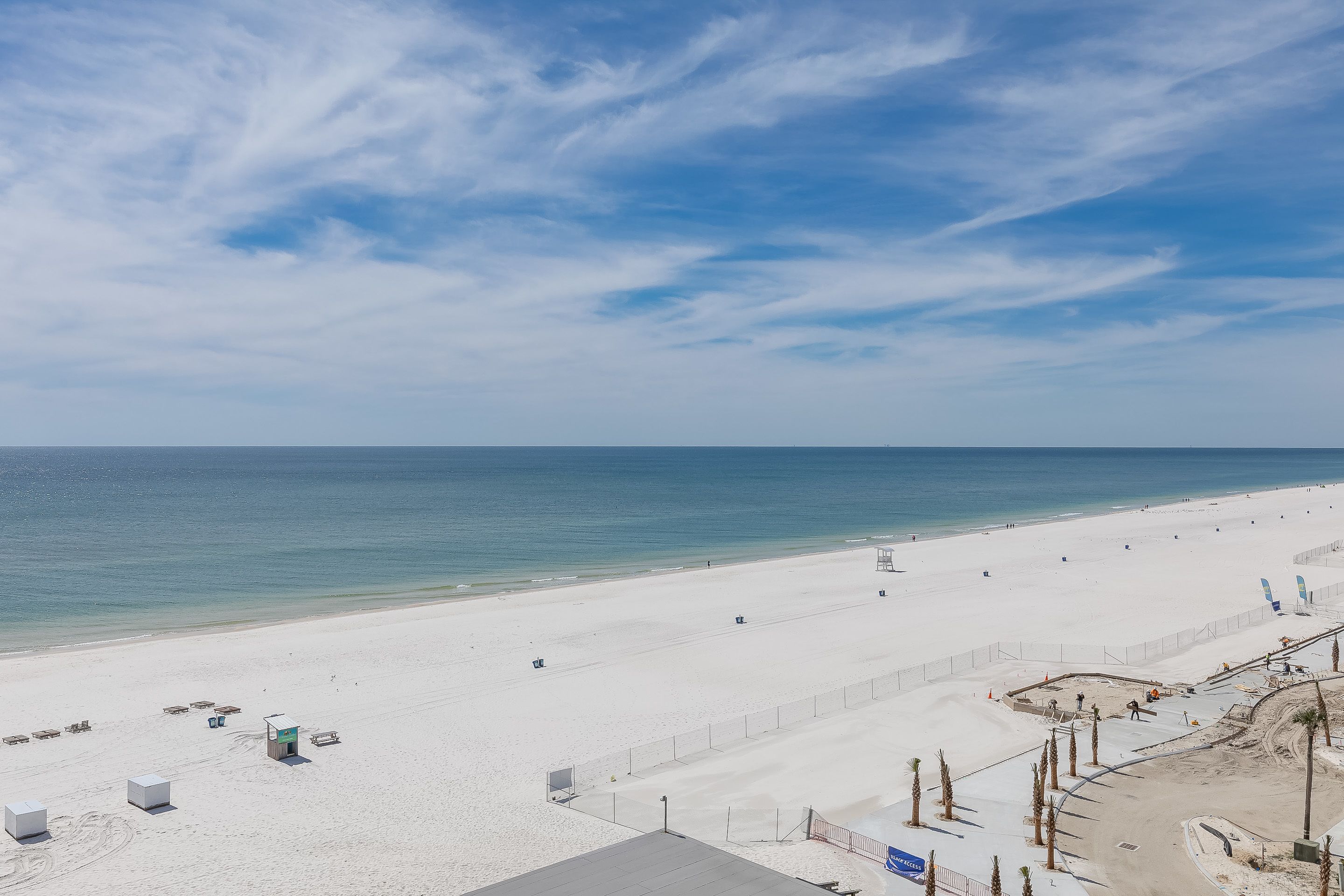 A beach with a sandy shore, a few lifeguard towers, and a clear blue sky.