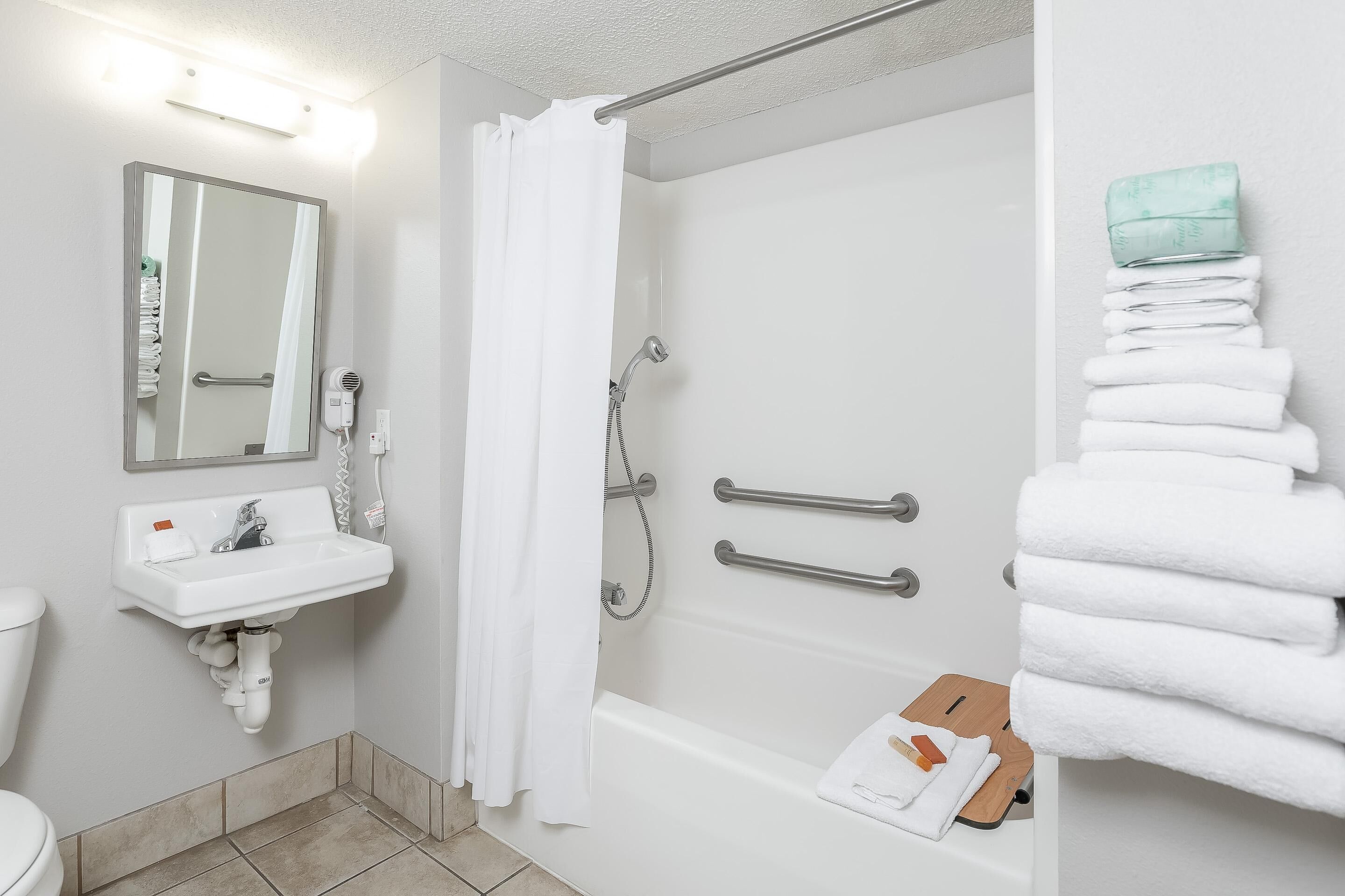 A bathroom with a sink, mirror, shower, and towel rack.