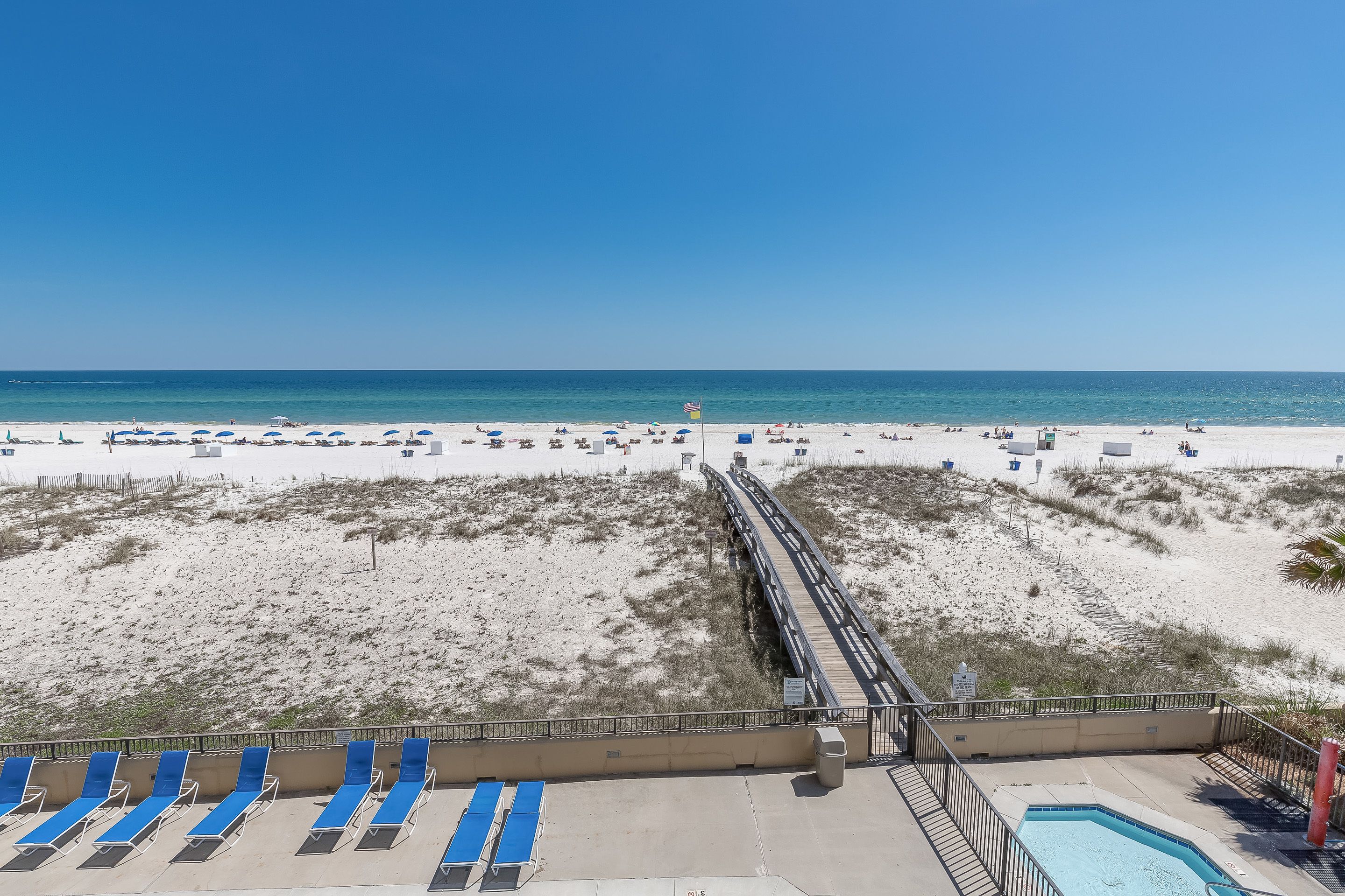 A beach view with a pool and lounge chairs.
