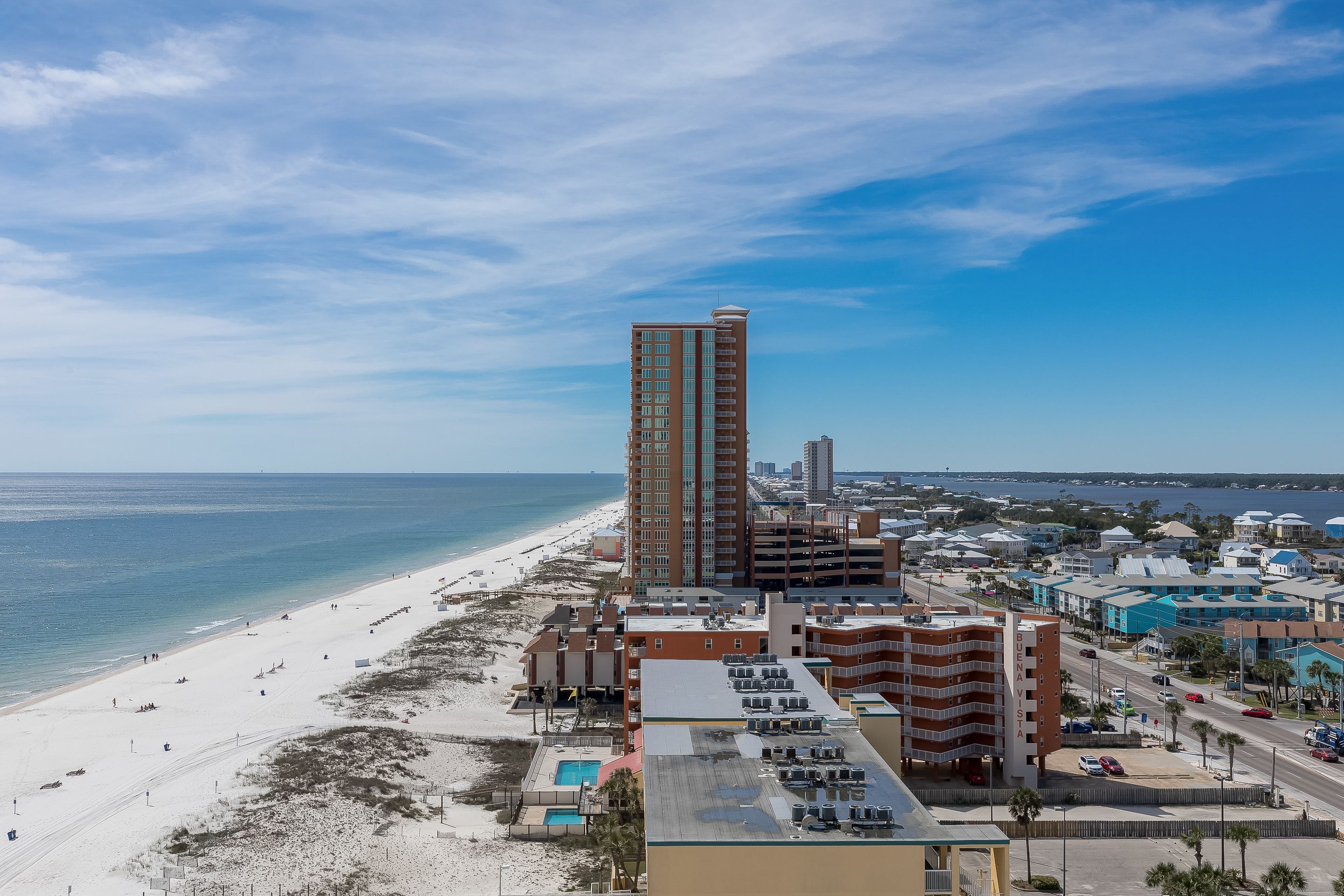 A coastal cityscape with a tall hotel, beach, and ocean.
